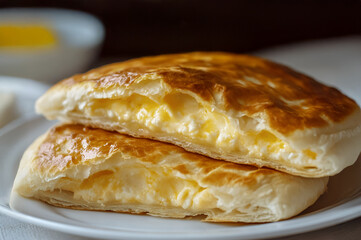 Flaky pastry layers filled with creamy cheese, served on a white plate, showcasing golden-brown texture and appetizing appearance, ideal for food photography and culinary presentations