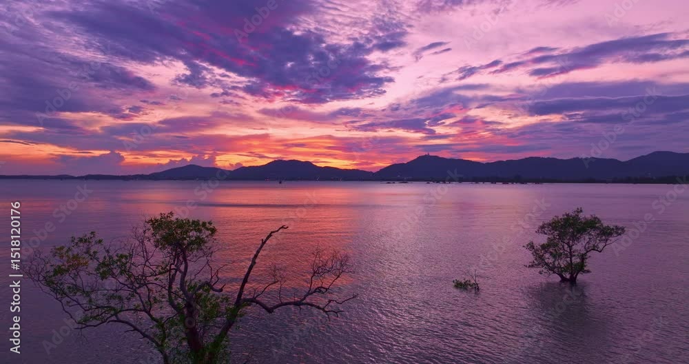 Wall mural aerial view of a tranquil sunset over a calm coastal landscape, with colorful sunset behind distant 