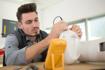 electrician testing appliance with multimeter