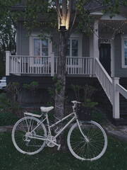 Un vélo devant une maison avec une lampe le soir. Un vélo fantôme devant une maison.
