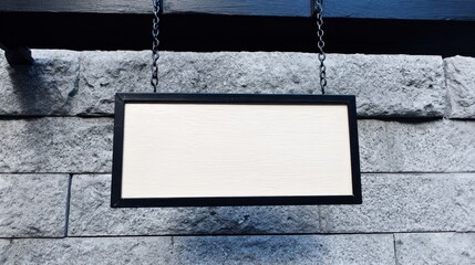 Blank rectangular signboard hanging on a stone wall, ready for custom text or design.