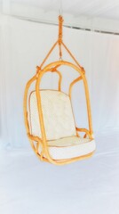 A cozy, modern hanging chair with a cushion, suspended by ropes against a plain white background.