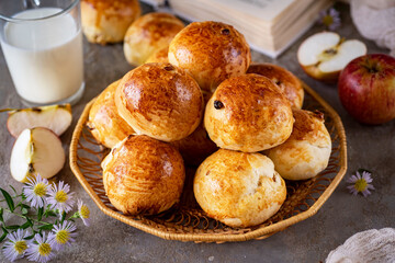 Sweet buns with raisins for breakfast in a basket on a gray background. Close-up