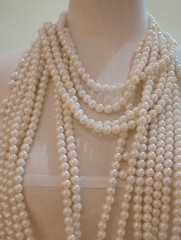 Pearl necklace on a mannequin in a shop window.