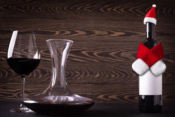 Decanter, glass and santa claus hat and scarf on bottle with red wine on wooden rustic background. Christmas   celebration