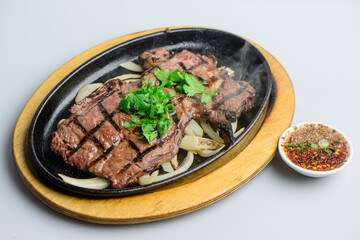 Sizzling Grilled Beef Steak with Fresh Cilantro on Hot Plate