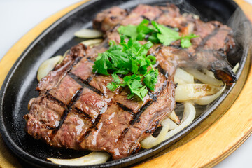 Sizzling Grilled Beef Steak with Fresh Cilantro on Hot Plate