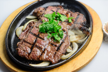 Sizzling Grilled Beef Steak with Fresh Cilantro on Hot Plate