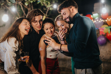 A group of close friends is enjoying a gathering, sharing laughter and joy while looking at a smart...