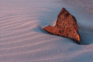 a bronze colored piece of metal buried in sand