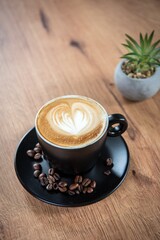 A cozy cup of cappuccino with heart-shaped latte art, resting on a wooden table beside a small succulent—inviting a quiet and peaceful coffee moment.