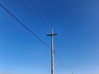 Electric pole and electric cables with blue sky background