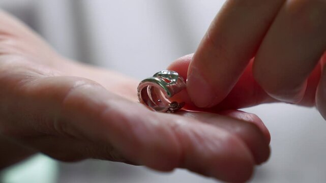 Jewelry. Hands close-up.
Silver earring in the hands of a jeweler.
Jewelry repair.
A man chooses jewelry in a jewelry store