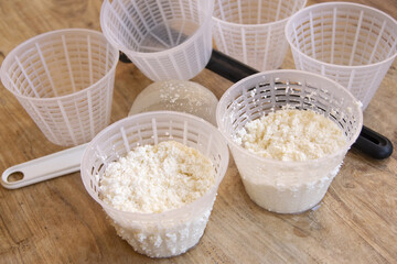 Cheesemaker preparing fresh ricotta cheese using plastic draining baskets and sieve