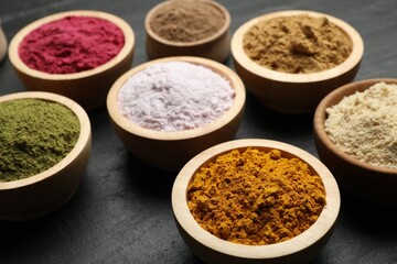 Different superfood powders on black table, closeup