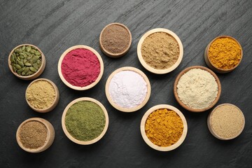 Different superfood powders on black table, flat lay