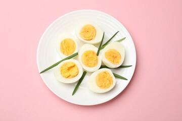 Boiled eggs and green onions on pink background, top view