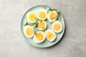 Hard boiled eggs with microgreens on grey table, top view
