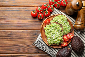 Delicious sandwiches with avocado, sesame seeds, tomatoes and spices on wooden table, flat lay. Space for text