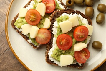 Delicious sandwiches with avocado, cheese and olives on table, top view