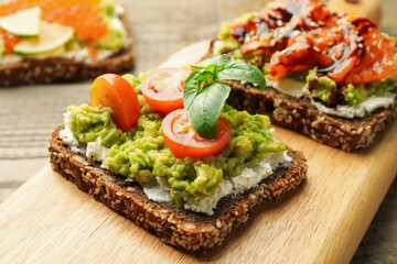 Different delicious avocado sandwiches on table, closeup