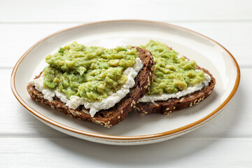 Delicious sandwiches with avocado and cream cheese on white wooden table, closeup