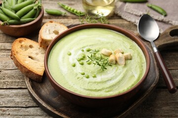 Tasty pea cream soup with croutons and thyme served on wooden table, closeup