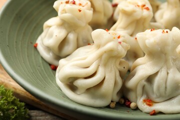 Delicious khinkali with spices in bowl on table, closeup