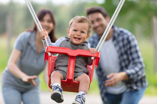 parents with adorable baby daughter playing with swing