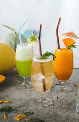 Colorful tropical fruit drinks with ice and garnishes in tall glasses