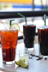 Colorful tropical fruit drinks with ice and garnishes in tall glasses