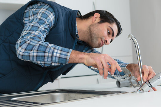 a plumber removing kitchen faucet