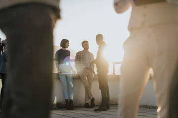 A group of business coworkers engaged in a casual conversation on a high tower balcony during...