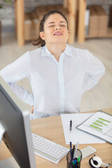 Fototapeta premium young woman having back pain while sitting at desk