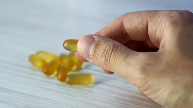 Omega 3 capsules in plan lie on a white table.
Scattered tablets on the table.
Gold vitamins with fish oil on the surface.
Healthy food.
Diet, nutrition, omega, natural, fish