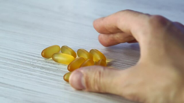 Omega 3 capsules in plan lie on a white table.
Scattered tablets on the table.
Gold vitamins with fish oil on the surface.
Healthy food.
Diet, nutrition, omega, natural, fish