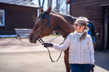 Portrait of a young woman with a horse at a rustic farm. Concept of rural lifestyle and countryside elegance.