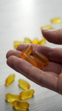 Omega 3 capsules in plan lie on a white table.
Scattered tablets on the table.
Gold vitamins with fish oil on the surface.
Healthy food.
Diet, nutrition, omega, natural, fish