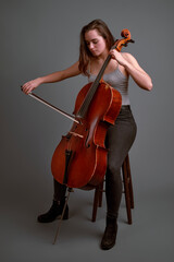 Young musician playing cello with passion and skill on grey background