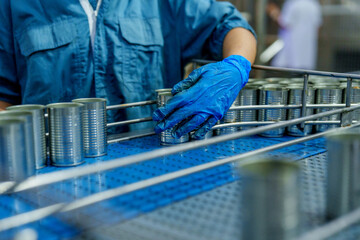 Fish processing industry relies on meticulous handling and packaging to ensure quality and safety. Workers in protective gear carefully manage canned products, showcasing dedication and precision