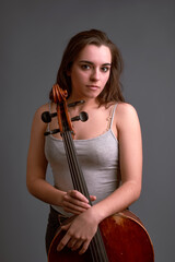 Young musician holding a cello with gray background