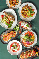 A vibrant assortment of gourmet dishes elegantly presented on a table, featuring grilled fish, roasted vegetables, fresh salads, and appetizers, showcasing rich colors and textures