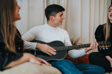 A group of friends relax in a cozy setting, enjoying music played with a guitar, surrounded by...