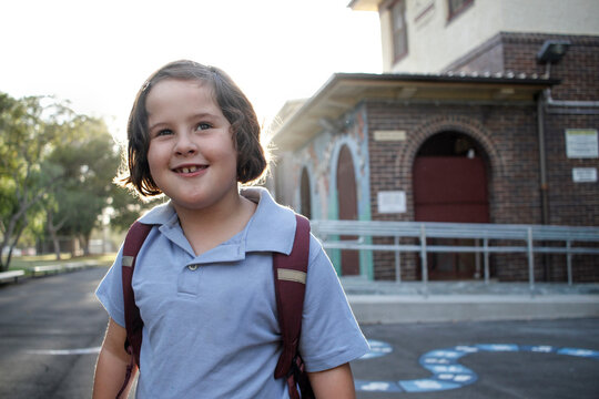 Young girl wearing backpack outside school building