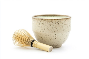 ceramic cup filled with frothy matcha green tea sits beside a traditional bamboo chasen (whisk), both placed against a clean white background