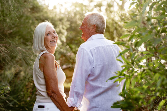 Senior couple holding hands while walking in public park