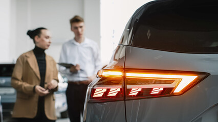 A customer at a car dealership consults with a salesperson, choosing a new vehicle. Concept: a...