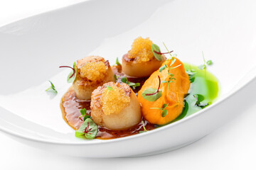 Fried scallops with fish caviar and sauce on plate isolated on white background. Seafood, close up, top view