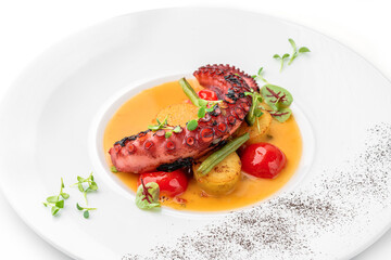 Grilled octopus with vegetables and sauce in plate isolated on white background. Healthy food, top view, close up