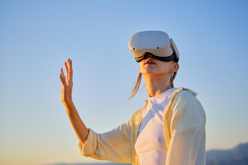 Young woman exploring virtual reality outdoors at sunset